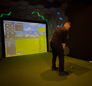 Futuristisch aussehender Golf Simulator mit Golfer auf der Abschlagsfläche