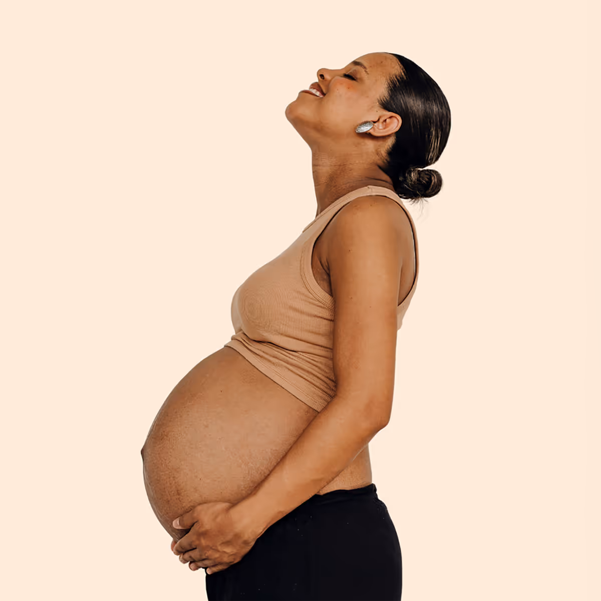 Happy pregnant mom smiling and looking up at the sky while cradling her belly
