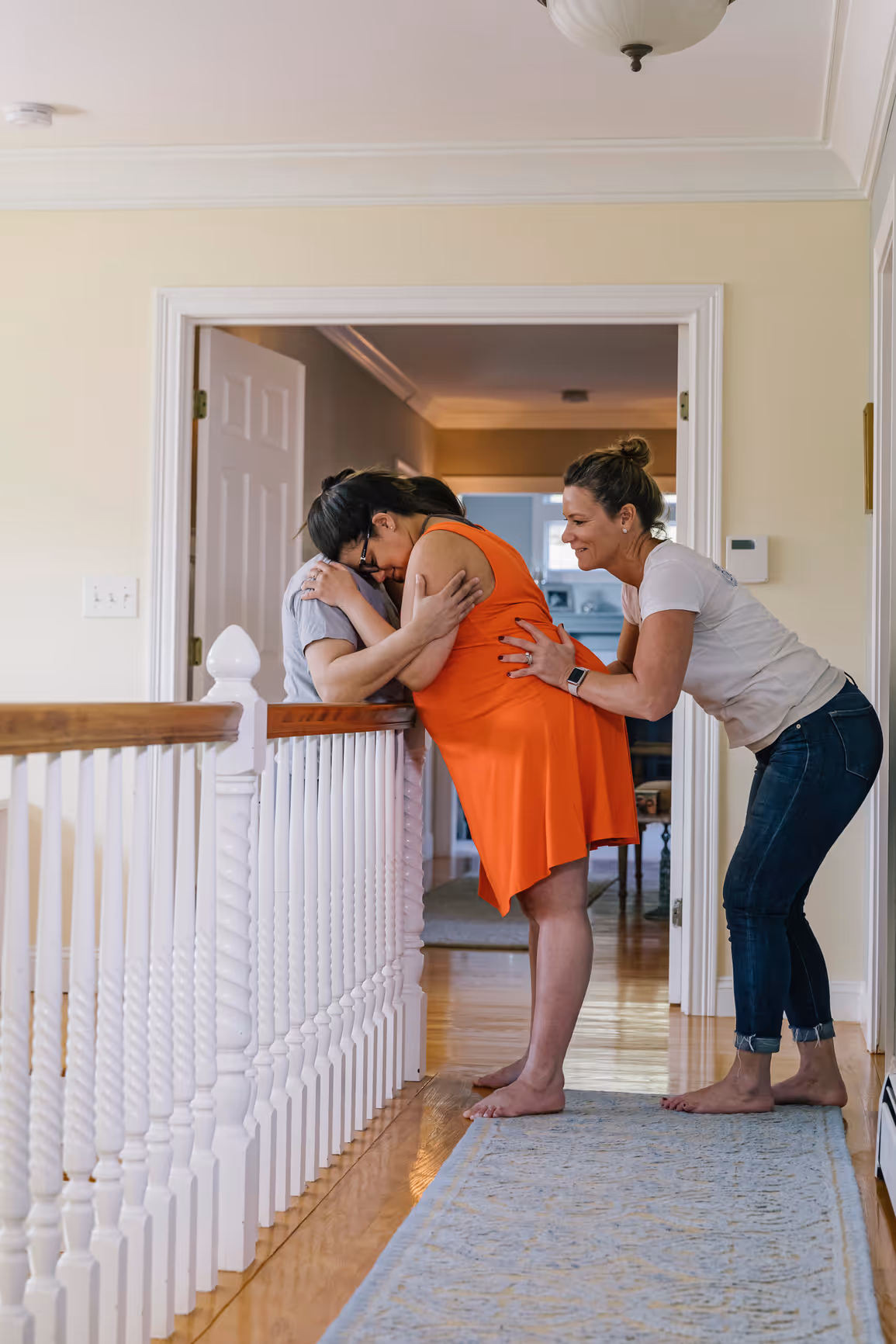 Doula providing hands-on labor support to pregnant person at home with partner assistance