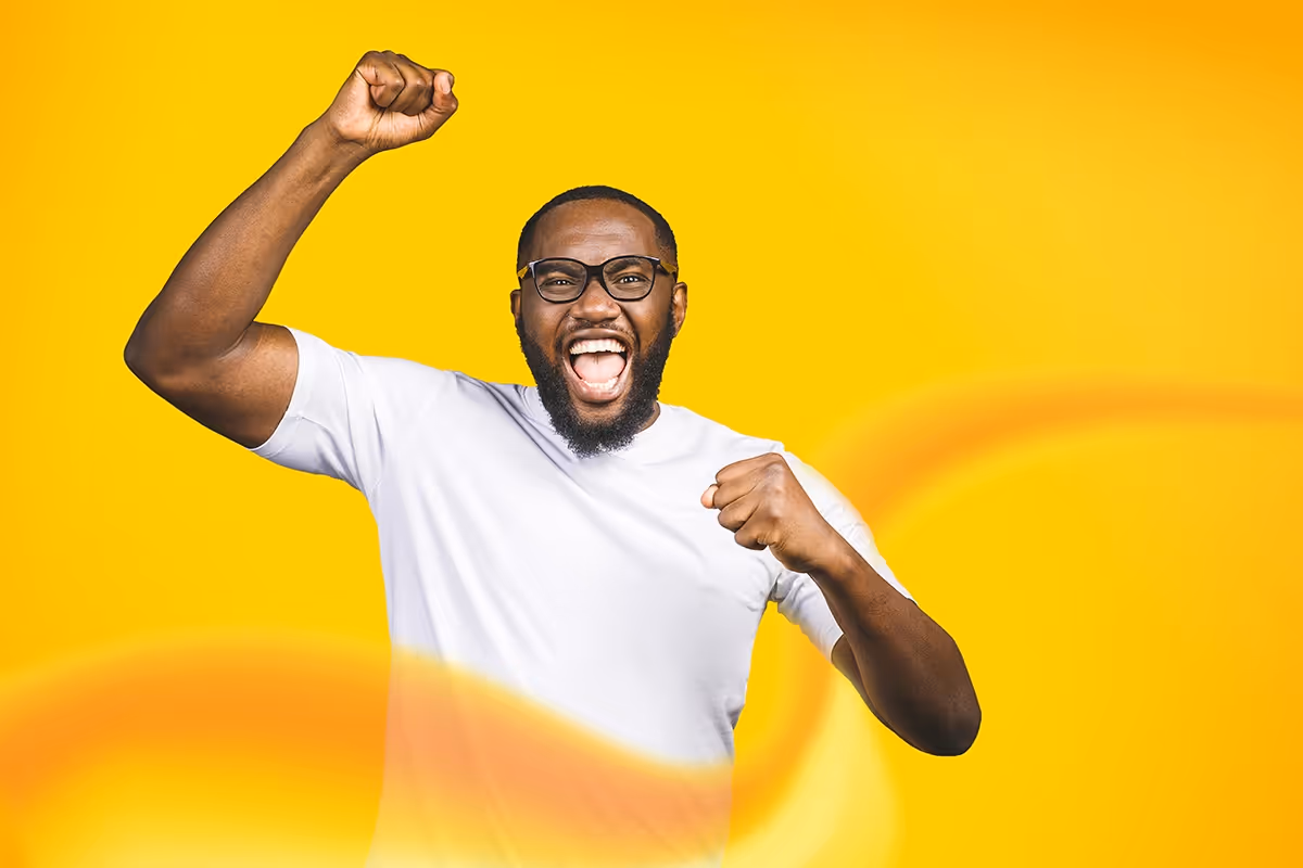 Man celebrating with hand in the air on yellow background