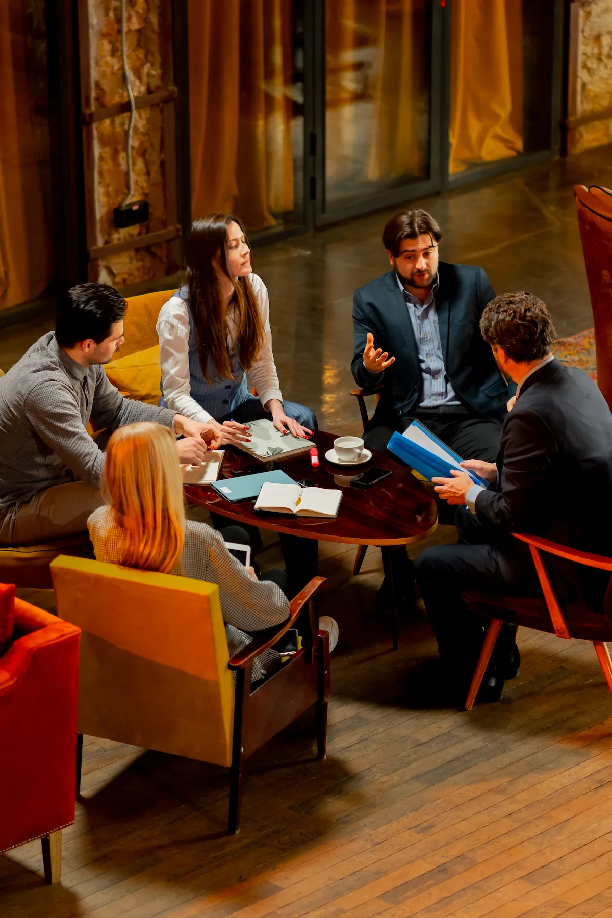 Cinq professionnels discutent et collaborent autour d'une table avec documents et café
