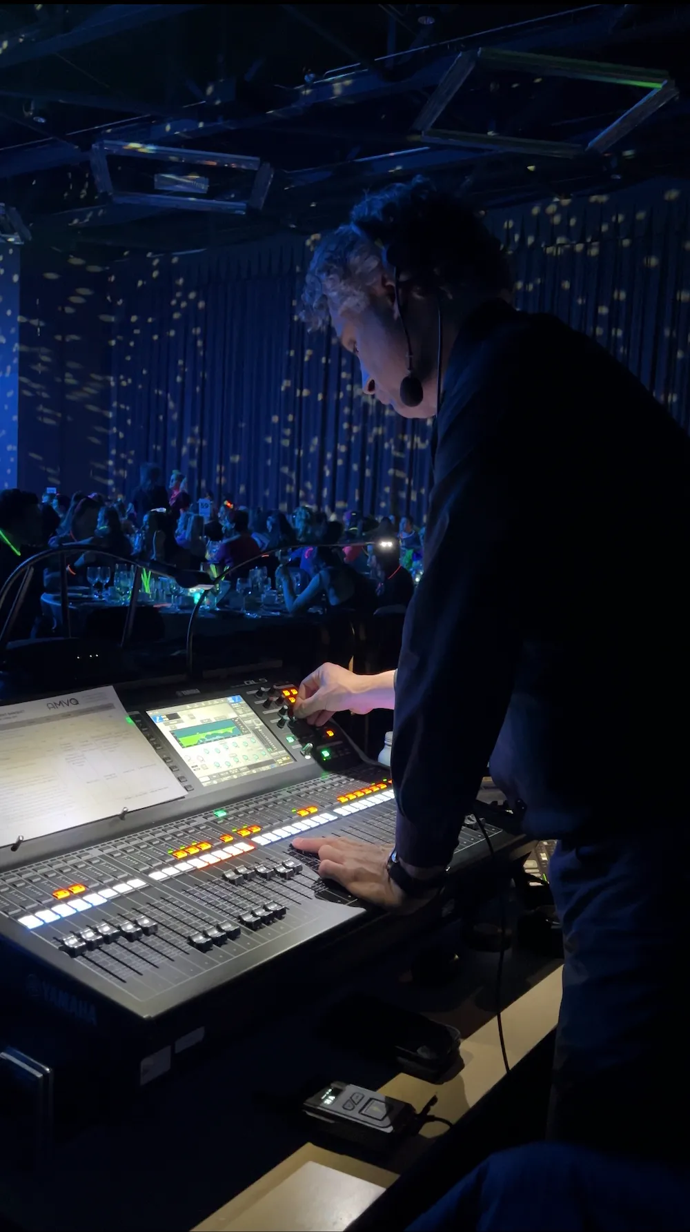 Technicien contrôlant une console d'éclairage lors d'un concert avec public visible