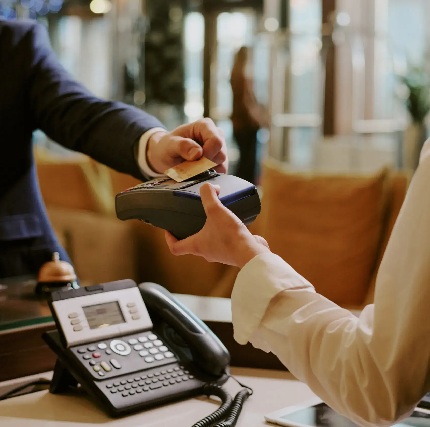 Person hands a credit card to another person holding a card reader for payment processing.