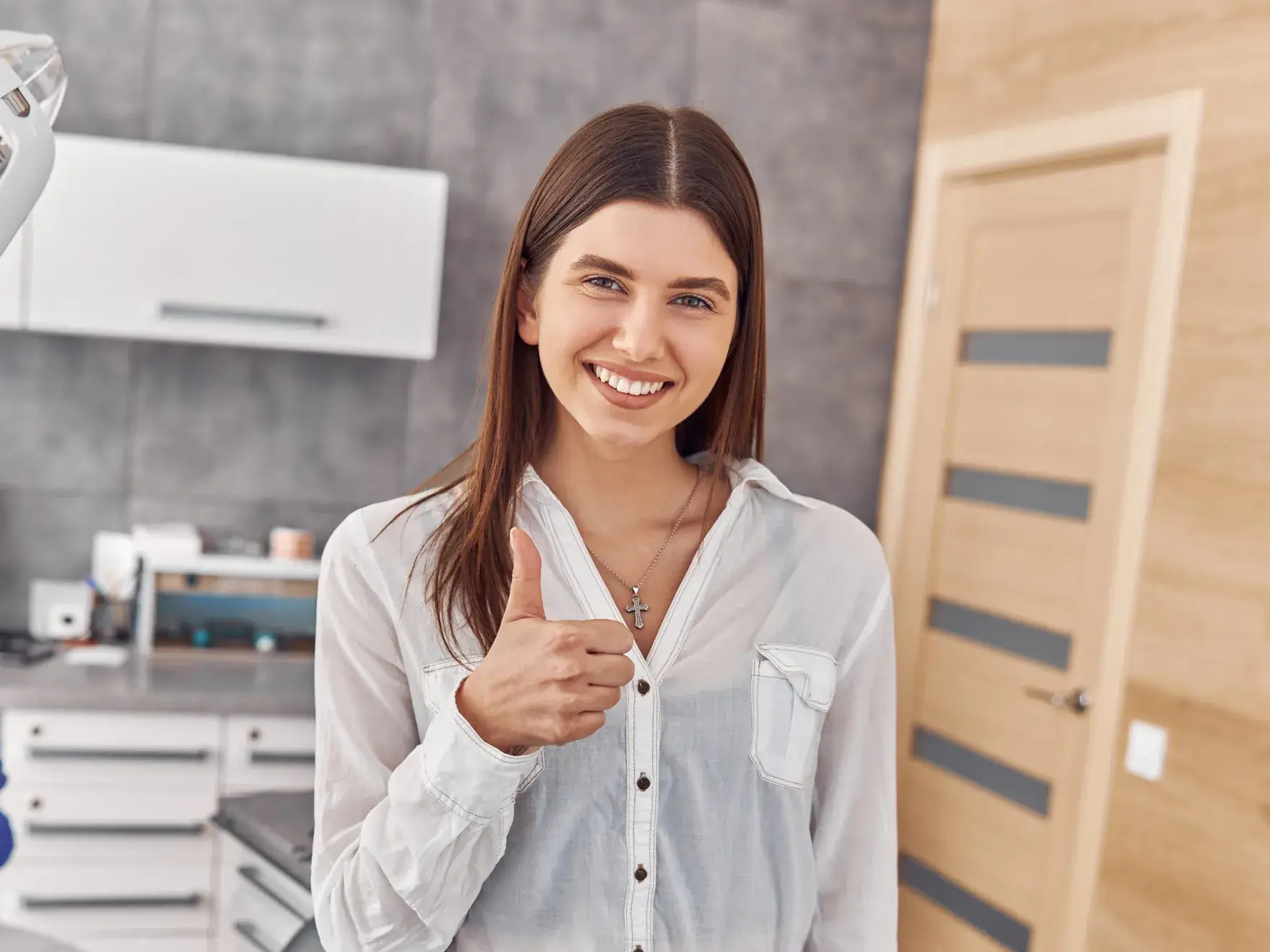 Woman in a white shirt giving a thumbs-up in a modern kitchen.