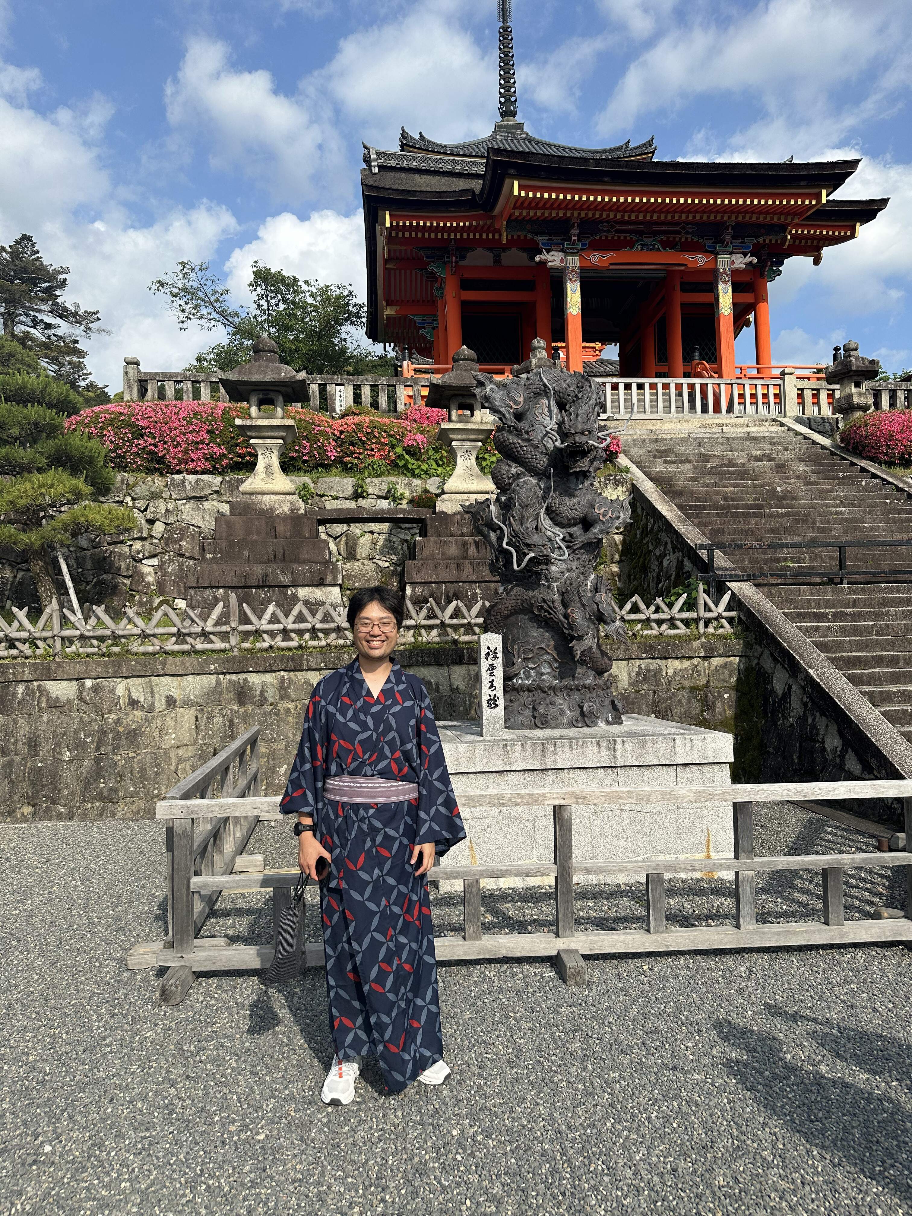 Mari-Alina Timoshchuk on a sunny day in Kyoto in front of a red temple and some steps in a dark blue kimono 