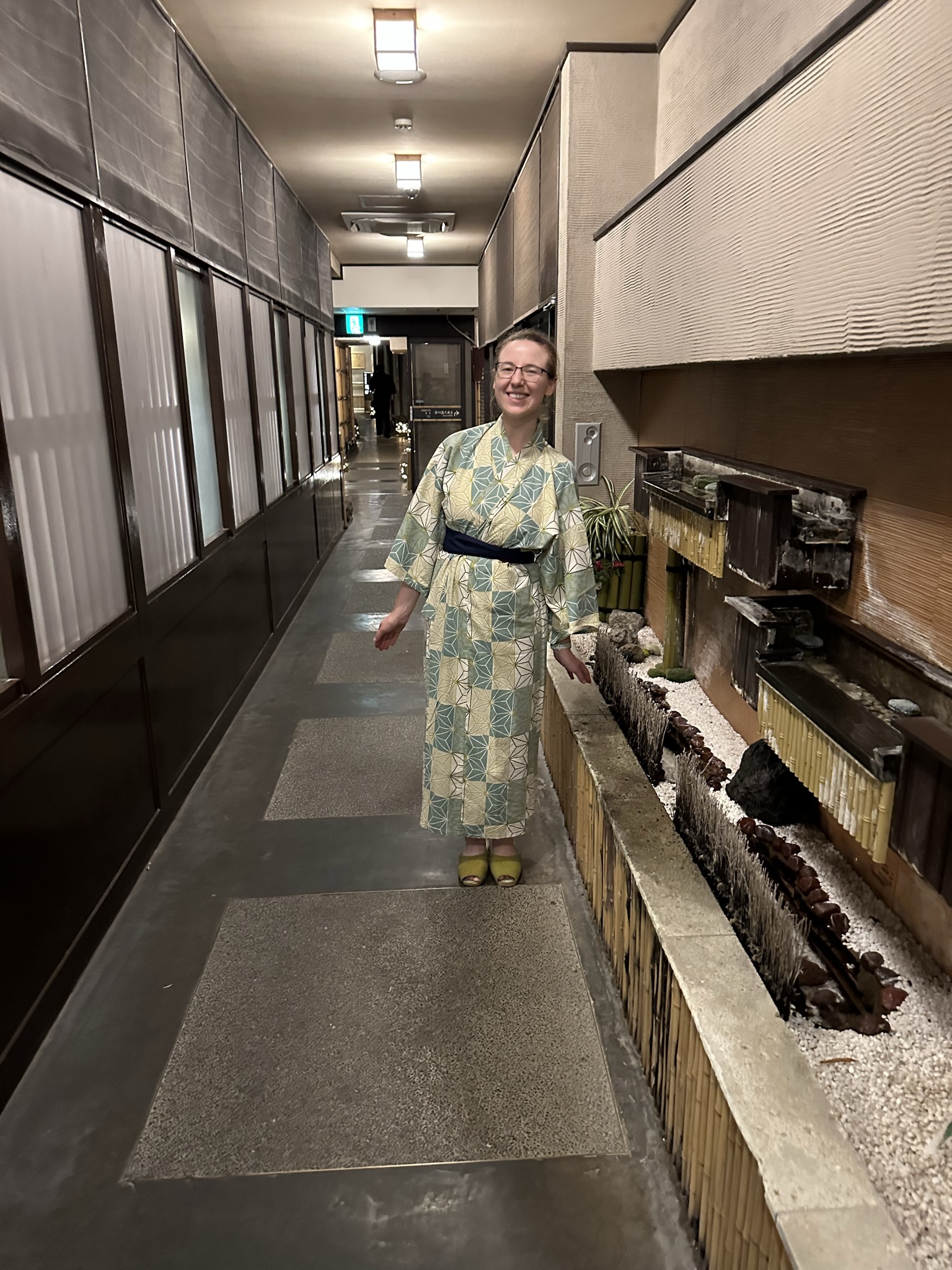Mari-Alina Timoshchuk in a hallway in a Japanese inn. She is wearing a blue and white kimono and smiling. 