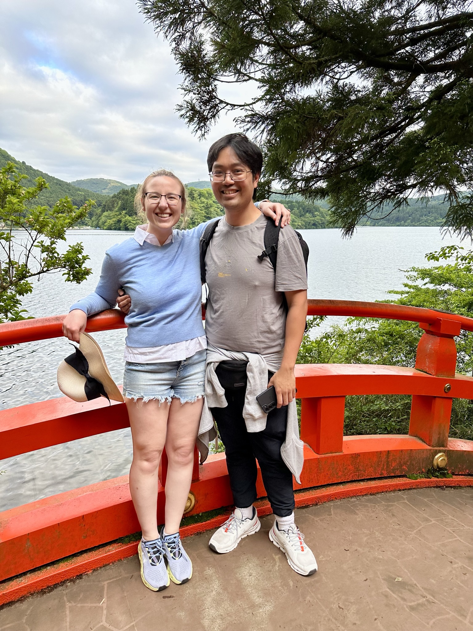 Mari-Alina Timoshchuk and Cassidy Sung standing on a red bridge at a shrine in Japan smiling