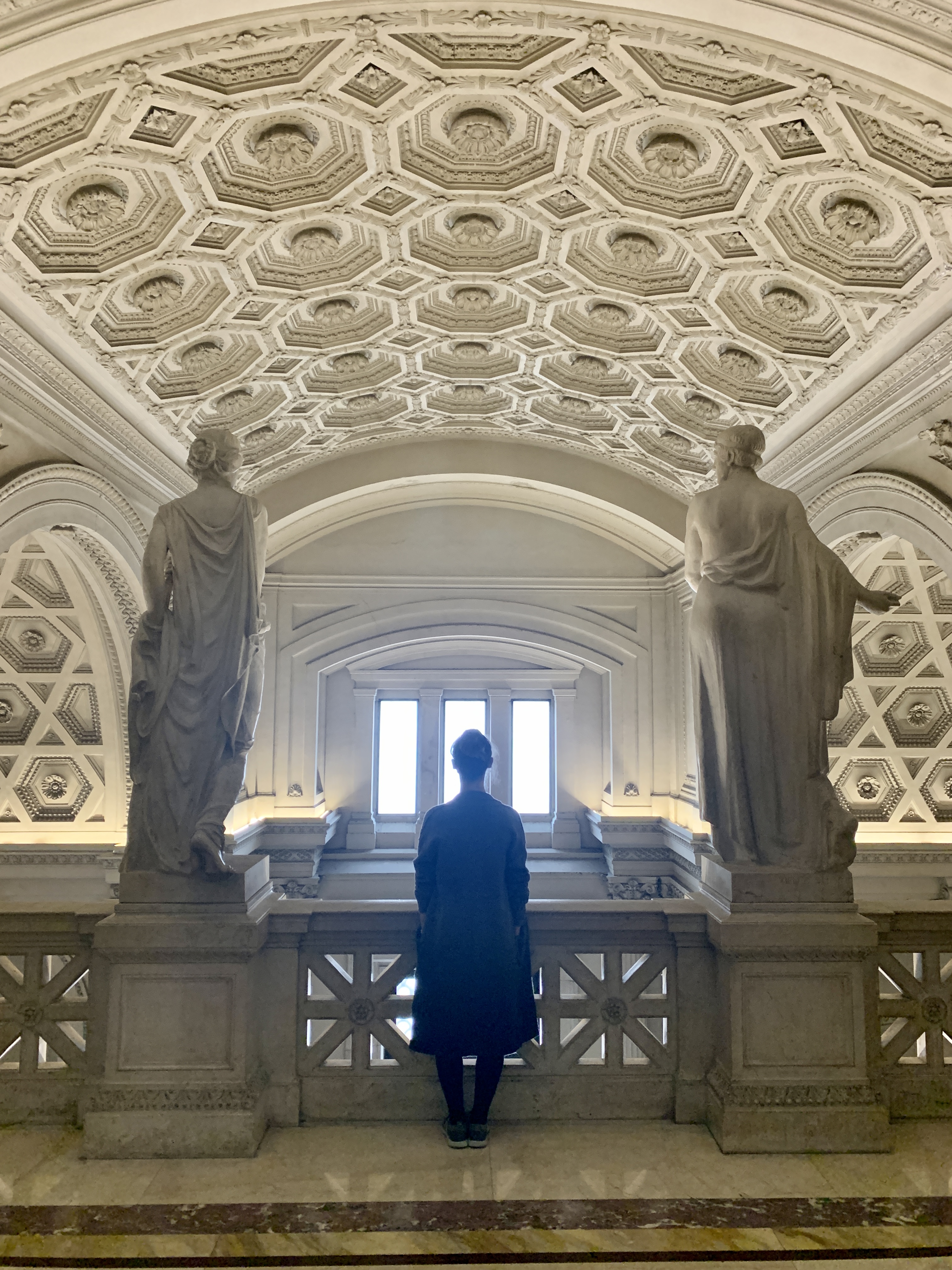Mari-Alina Timoshchuk in front of the parliament building in Rome facing a set of large windows with two surrounding Roman statues