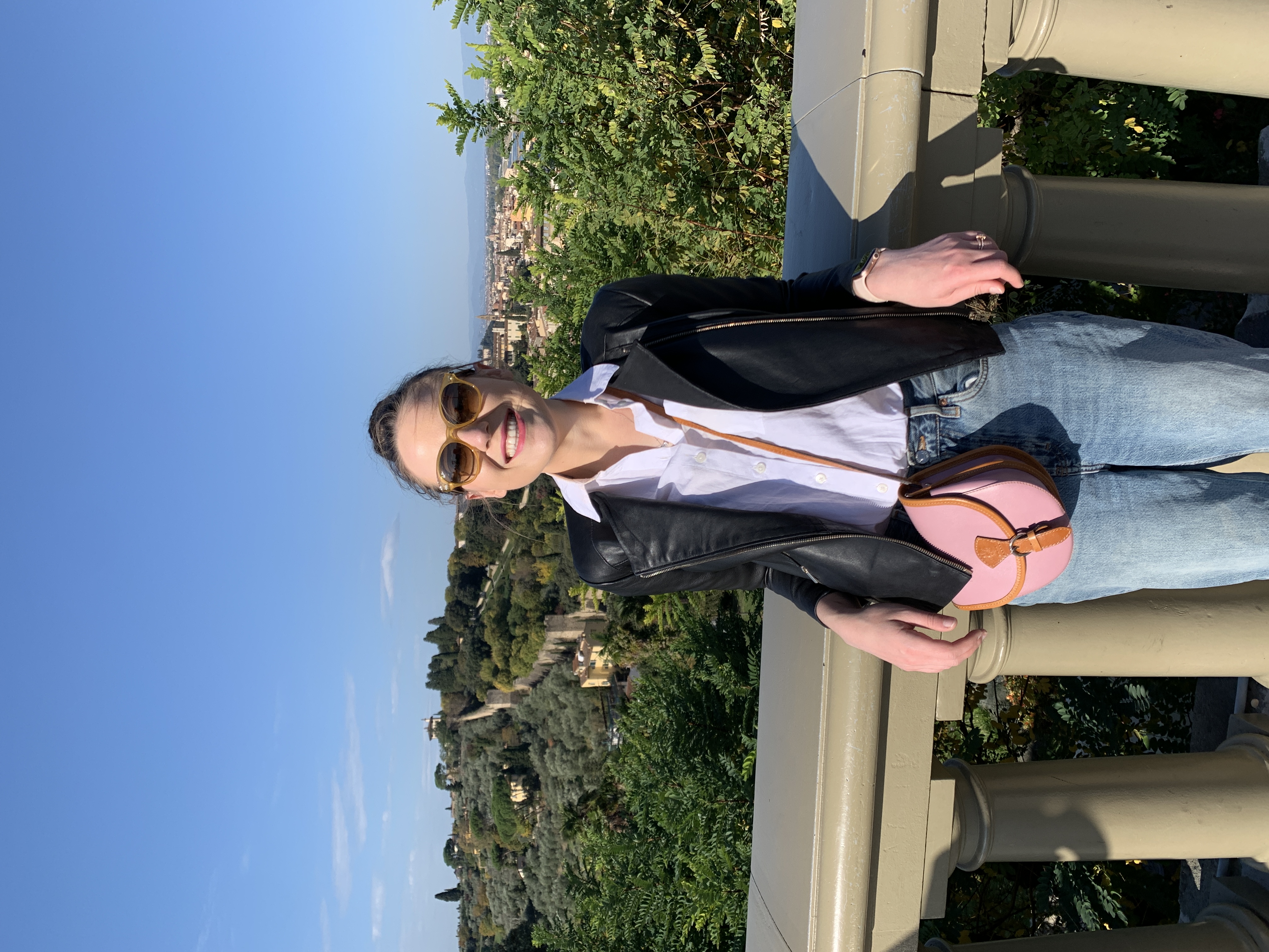 Mari-Alina Timoshchuk in Florence Italy leaning over some railing with trees in the background
