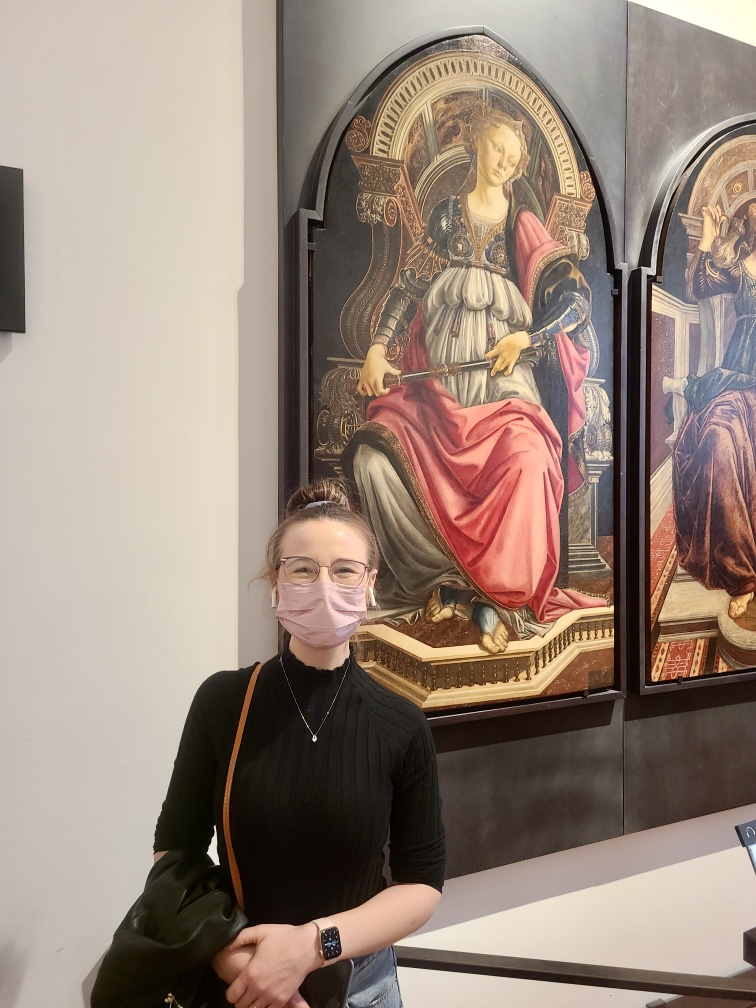 Mari-Alina Timoshchuk in the Uffizi gallery in Florence Italy standing next to a painting of a woman