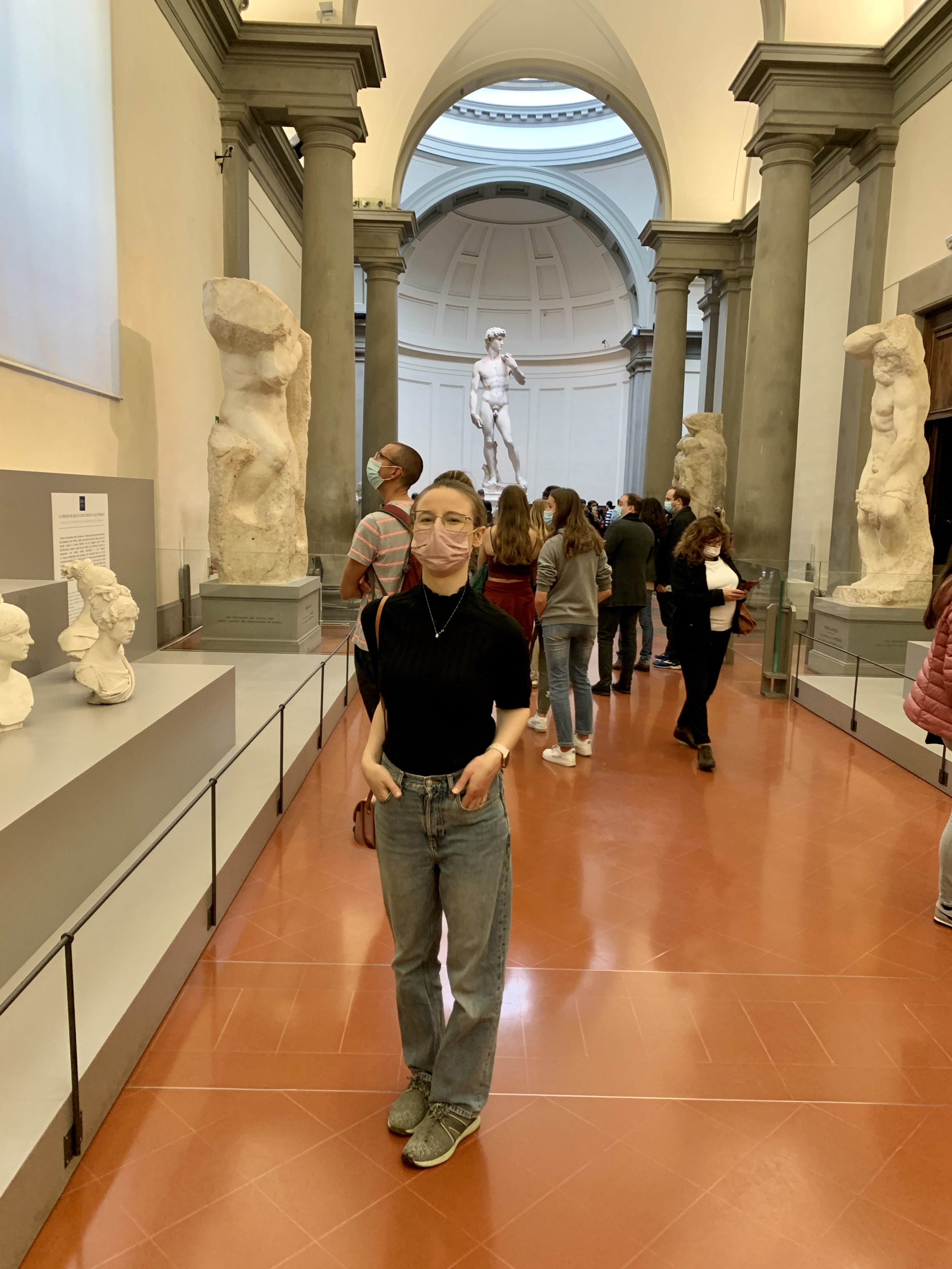 Mari-Alina Timoshchuk in the hall of an art gallery in Florence with the statue of David in the background