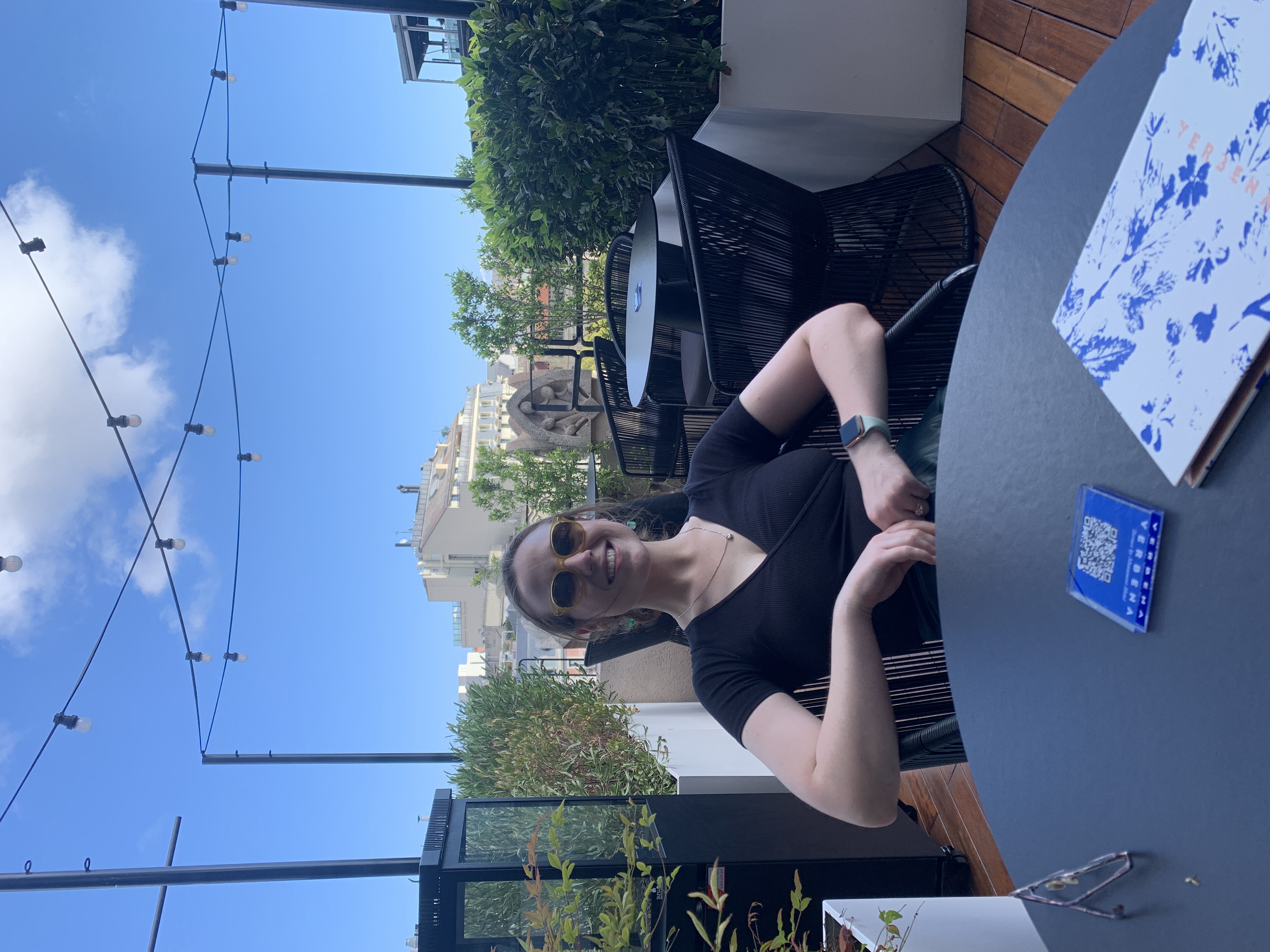Mari-Alina Timoshchuk sitting at a table in Italy wearing sunglasses and smiling