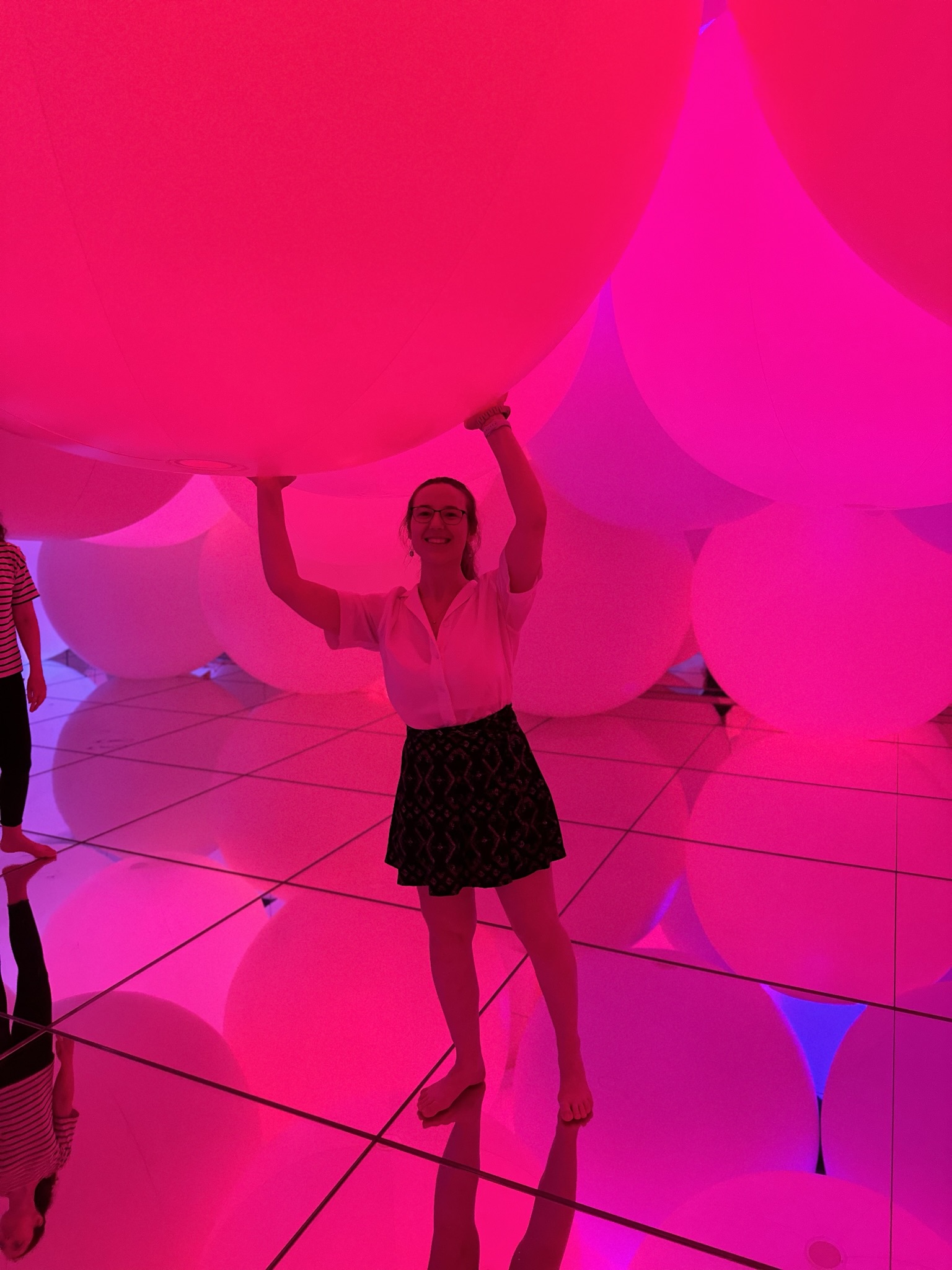 Mari-Alina Timoshchuk surrounded by large pink spheres holding up a pink sphere