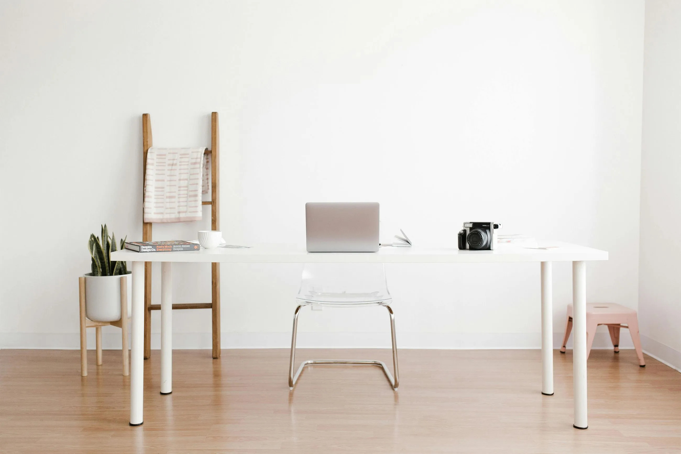 Minimalist workspace with laptop, camera, and white desk