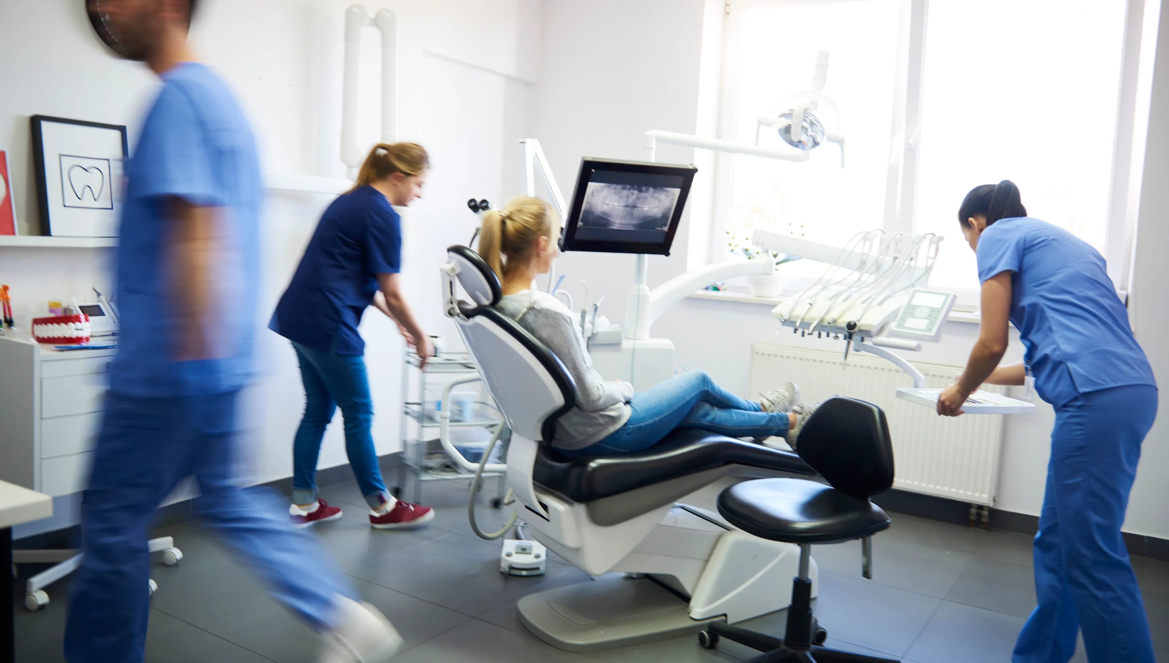A group of people standing around a dentist chair.
