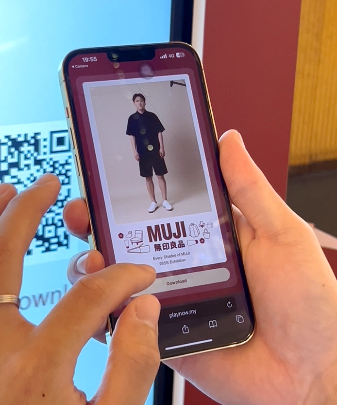 Hand holding a phone showing the MUJI SS26 styled outfit result.