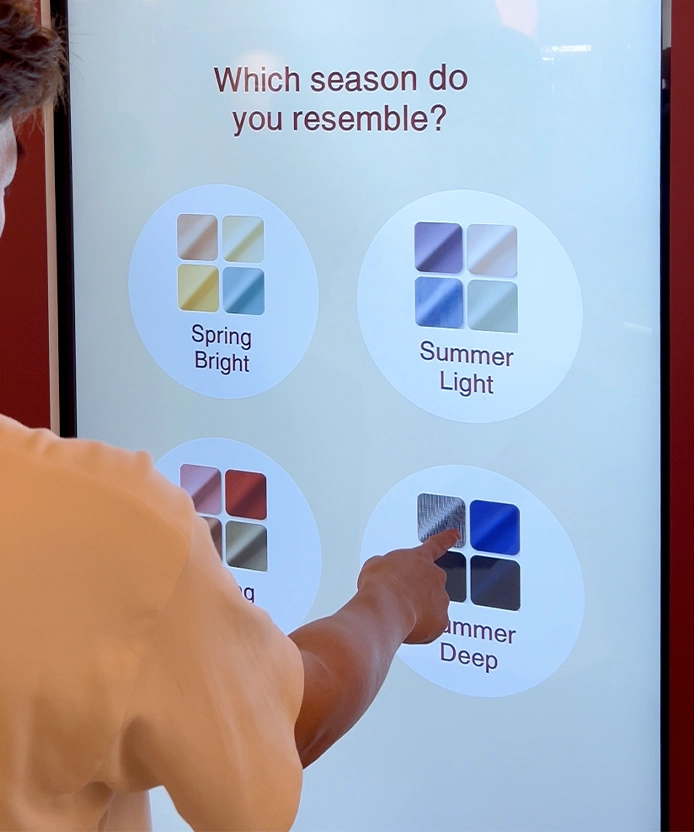 Shopper selecting a seasonal color palette on the MUJI kiosk screen.