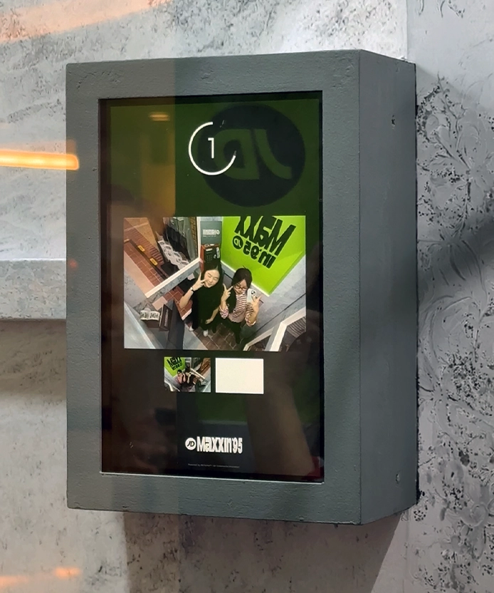 Wall-mounted touchscreen displaying the JD Maxxin 95 photo capture interface.