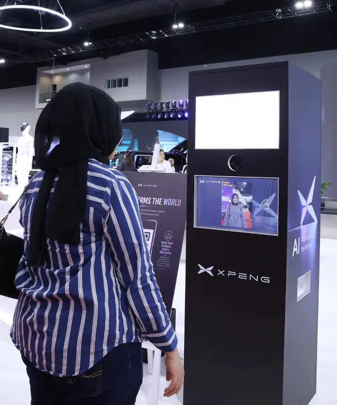 Visitor stepping up to the XPENG Instabox AI photobooth with her live camera preview on screen, KLIMS Malaysia