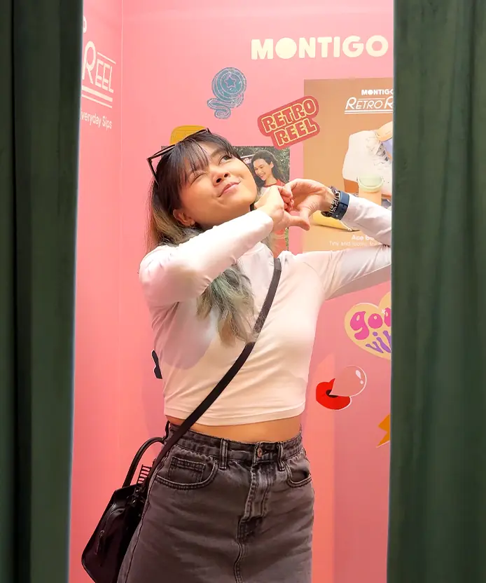Guest making a heart-hands pose inside the Montigo Retro Reel photobooth backdrop