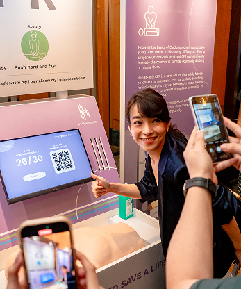Participant posing with her CPR training score and QR code results at the IHH interactive booth, Malaysia
