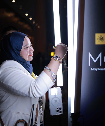 Guest drawing a glowing signature on the illuminated glass panel at the MGAN interactive drawing booth
