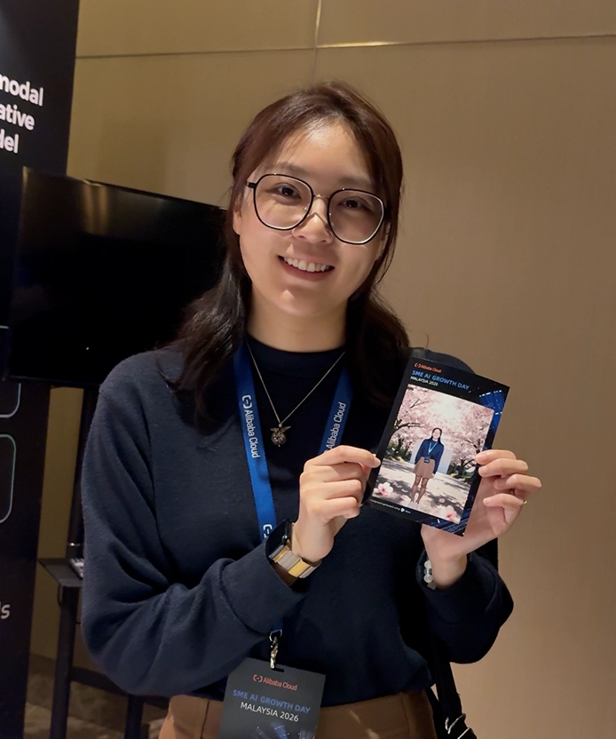 Attendee holding her Alibaba Cloud AI-generated cherry blossom portrait card at SME AI Growth Day Malaysia 2026