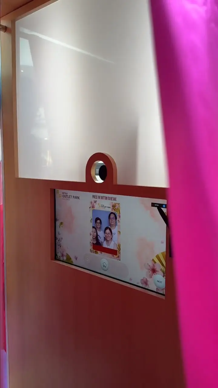 Inside the Mitsui Outlet Park calligraphy photo booth showing the retake screen with a group's captured photo