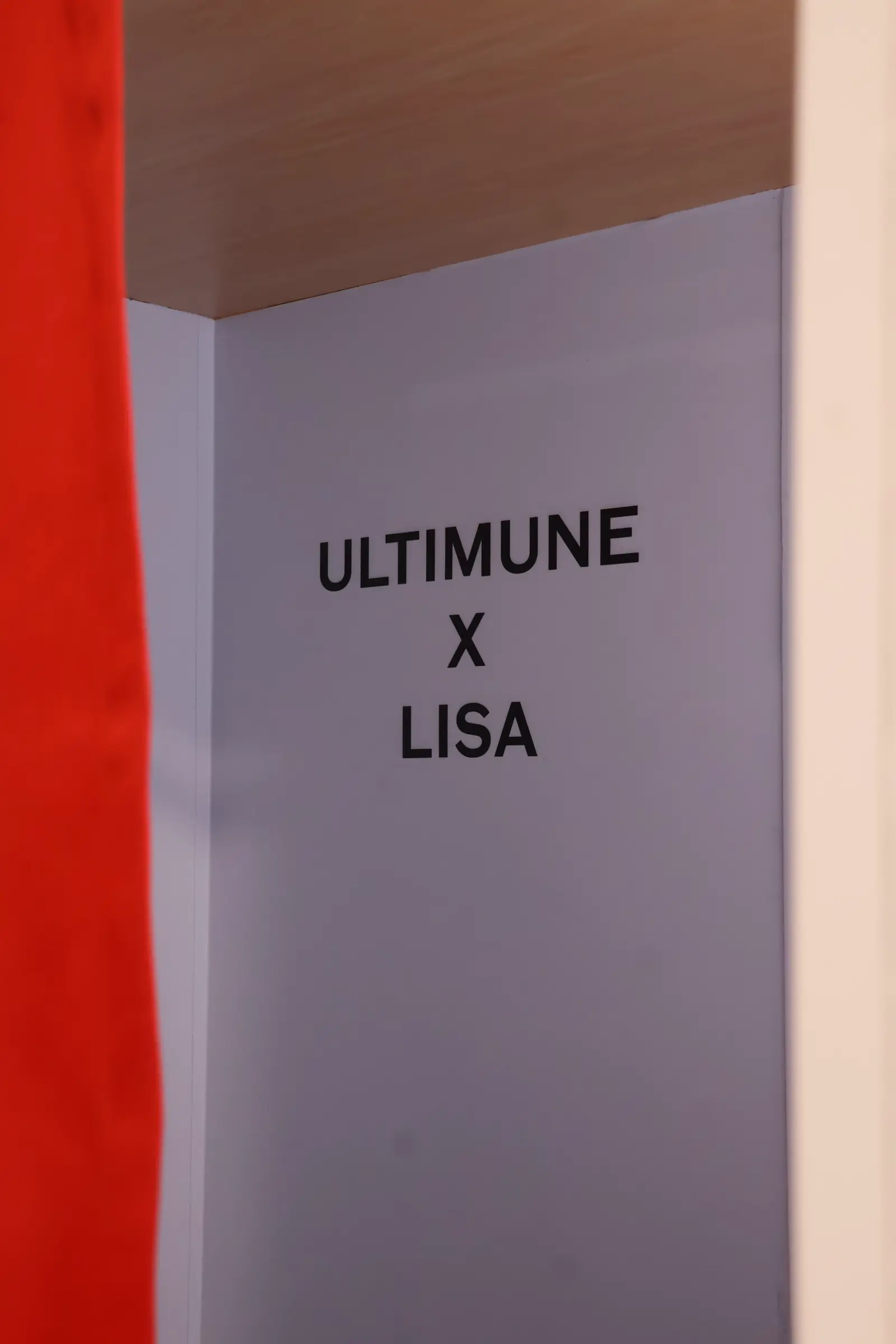 Lilac booth interior wall printed with the ULTIMUNE x LISA campaign branding beside a red curtain at the Shiseido pop-up