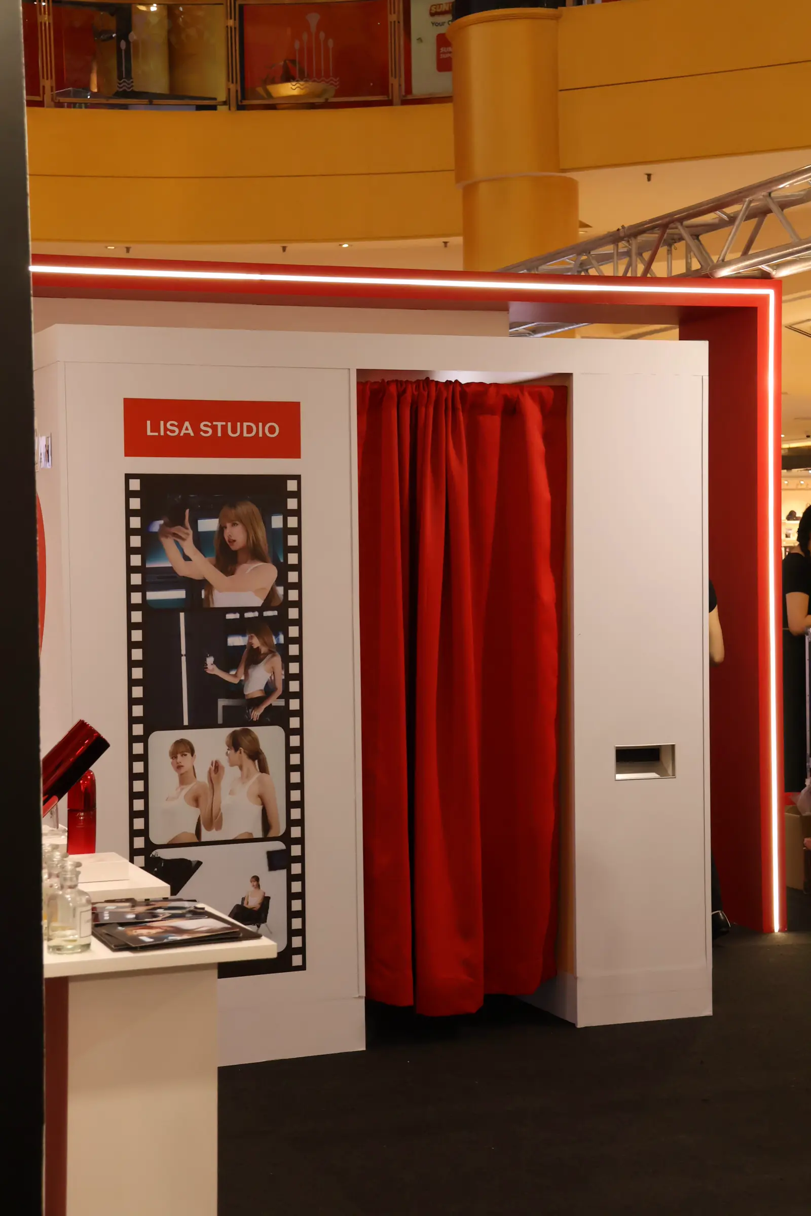 LISA Studio photo booth with red curtain entrance and film-strip display of LISA at a Shiseido ULTIMUNE pop-up in a shopping mall