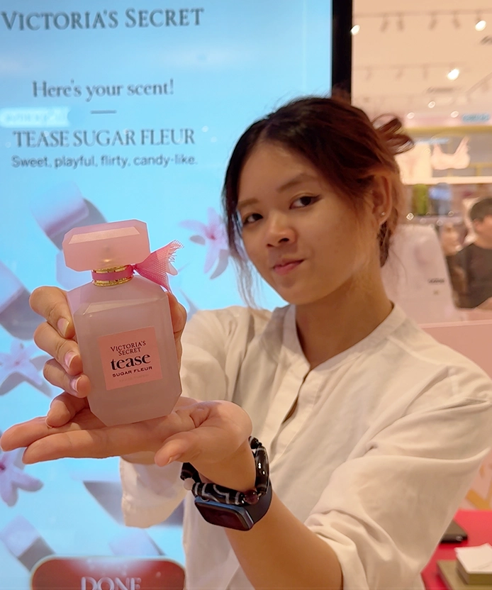 Woman presenting a Victoria's Secret Tease Sugar Fleur perfume bottle at the Pavilion KL, Kuala Lumpur scent-finder screen