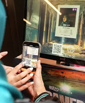 Guest scanning QR code on touchscreen displaying Astro Originals You've Been Framed branded photo Malaysia