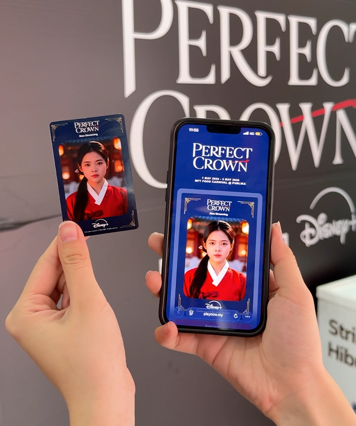 Printed Disney+ Perfect Crown sticker card next to a phone showing the same AI hanbok portrait at Publika, Kuala Lumpur