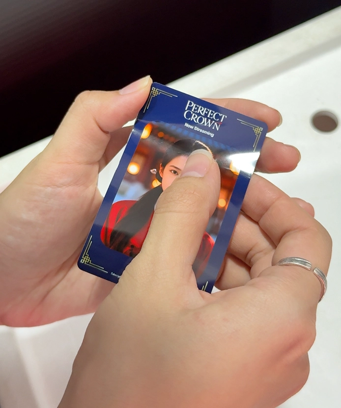 Hands holding a printed Perfect Crown photo card of the hanbok portrait.