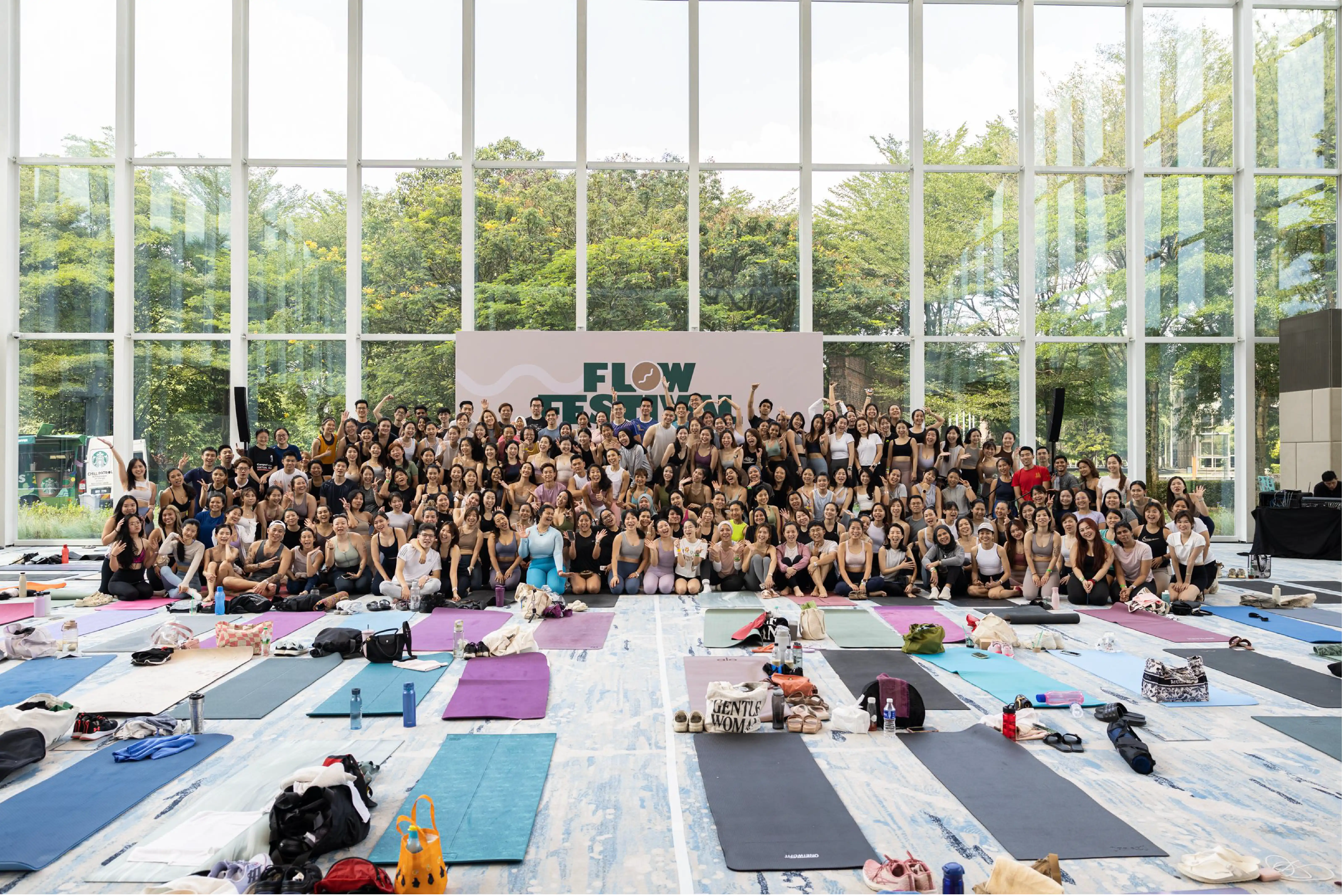 Large group of attendees posing together at Flow Fest 2025 with yoga mats on the floor