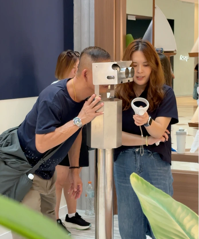A man looks into the viewfinder while a woman beside him holds the VR controller