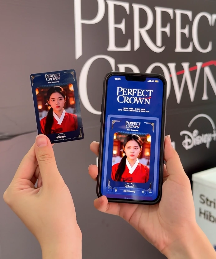 Printed Disney+ Perfect Crown sticker card next to a phone showing the same AI hanbok portrait at Publika, Kuala Lumpur