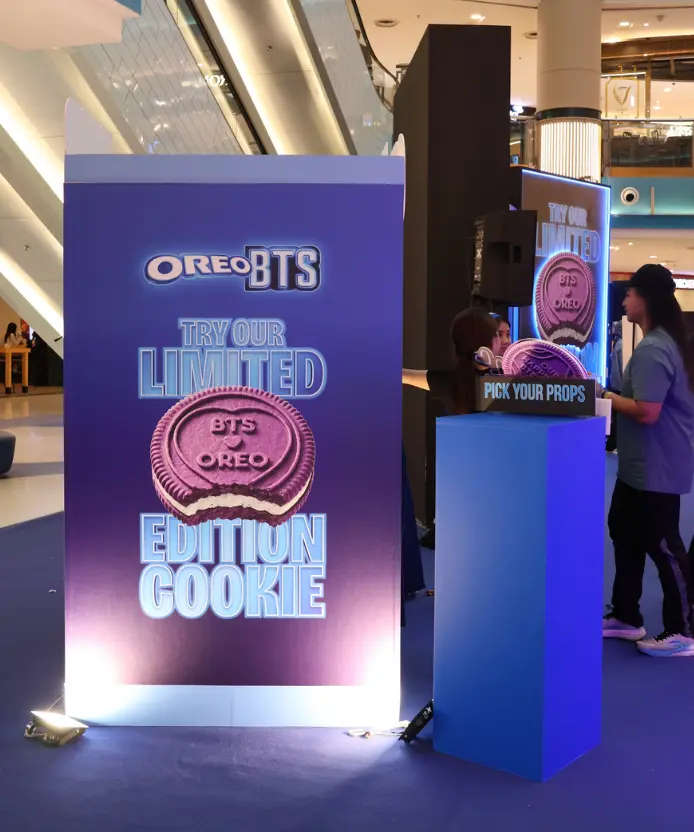 Illuminated purple standee reading "Oreo BTS — Try Our Limited Edition Cookie" featuring the pink BTS-embossed Oreo cookie, next to a blue "Pick Your Props" pedestal