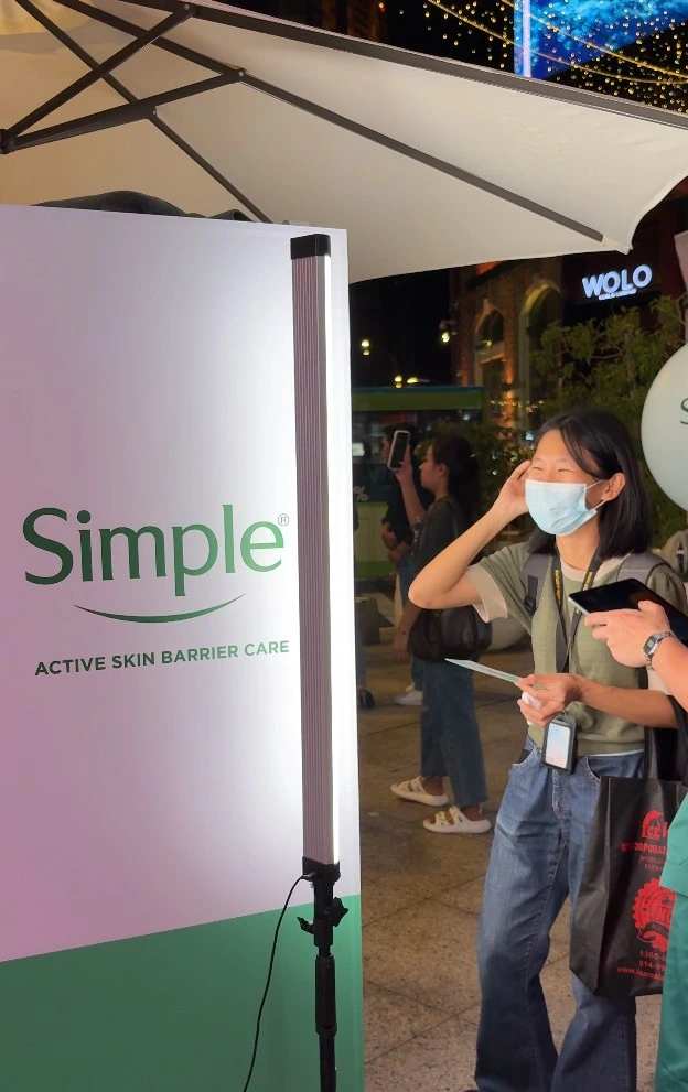 Guests queueing beside the Simple Active Skin Barrier Care display board