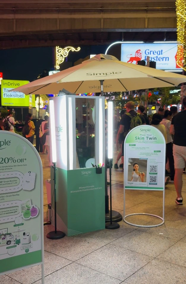 Simple "Meet Your Skin Twin" booth and signage on the street at night