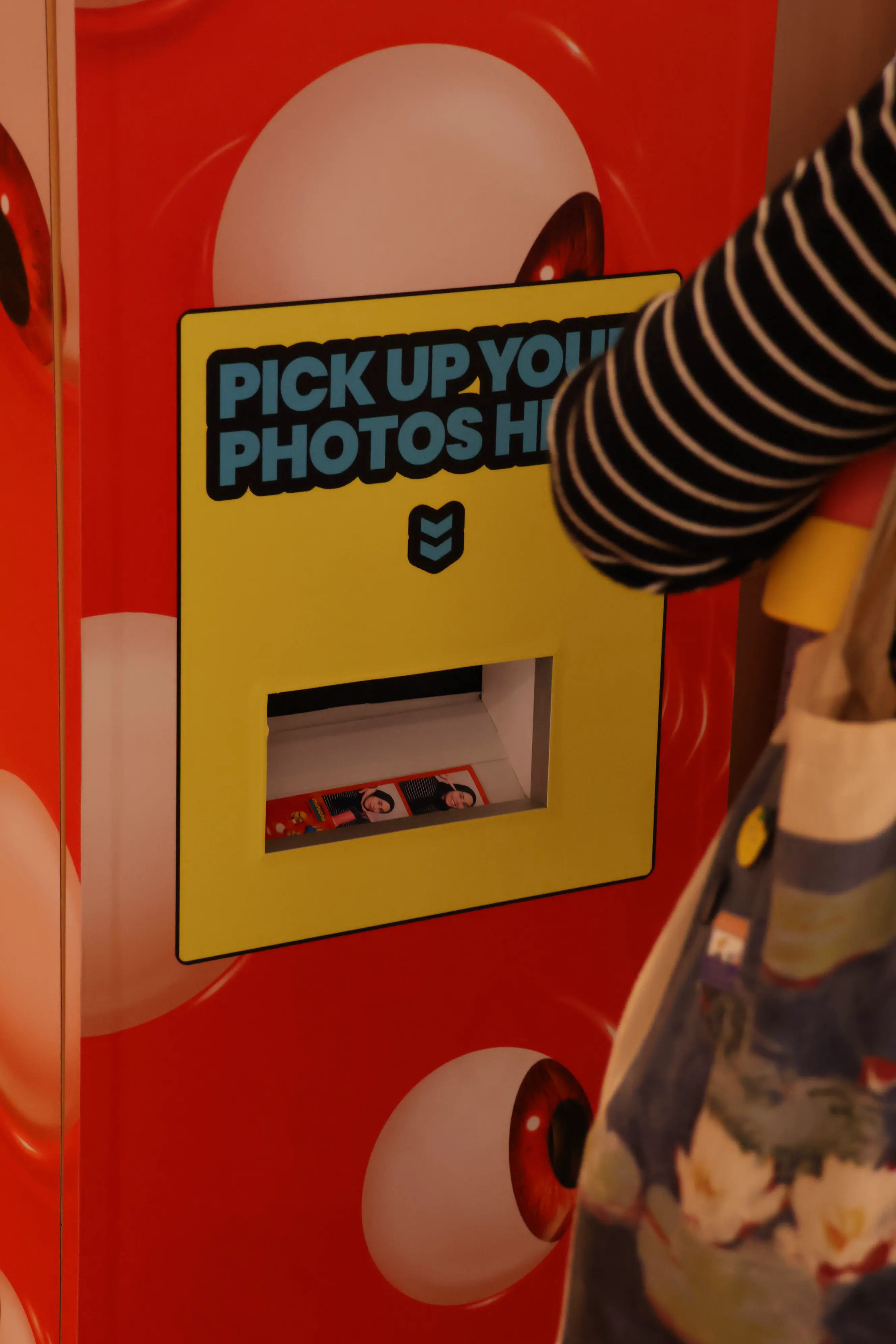 Guest collecting a printed photo strip from the booth's yellow pick-up slot
