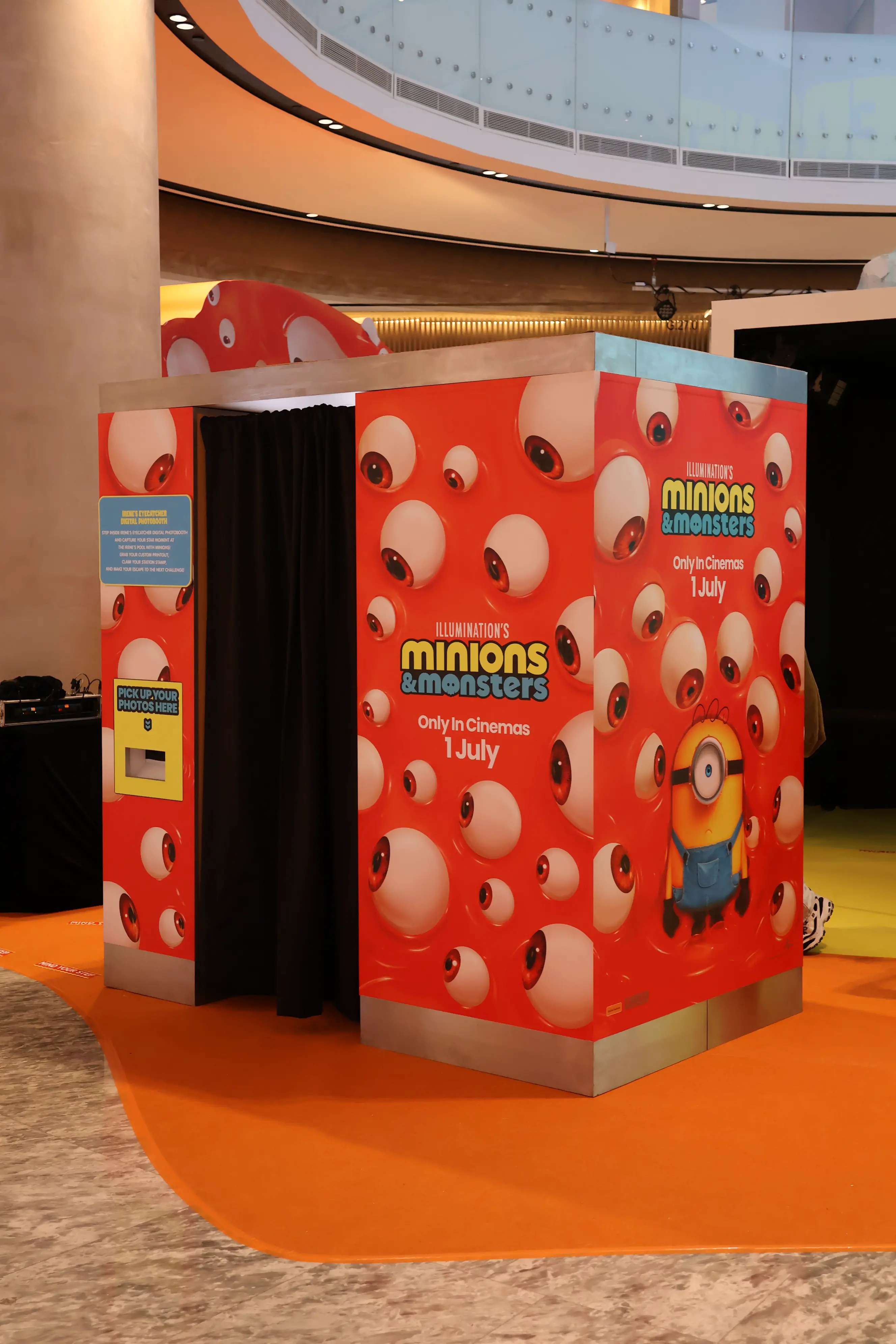 Red eyeball-patterned Minions & Monsters photo booth with black curtain in the mall