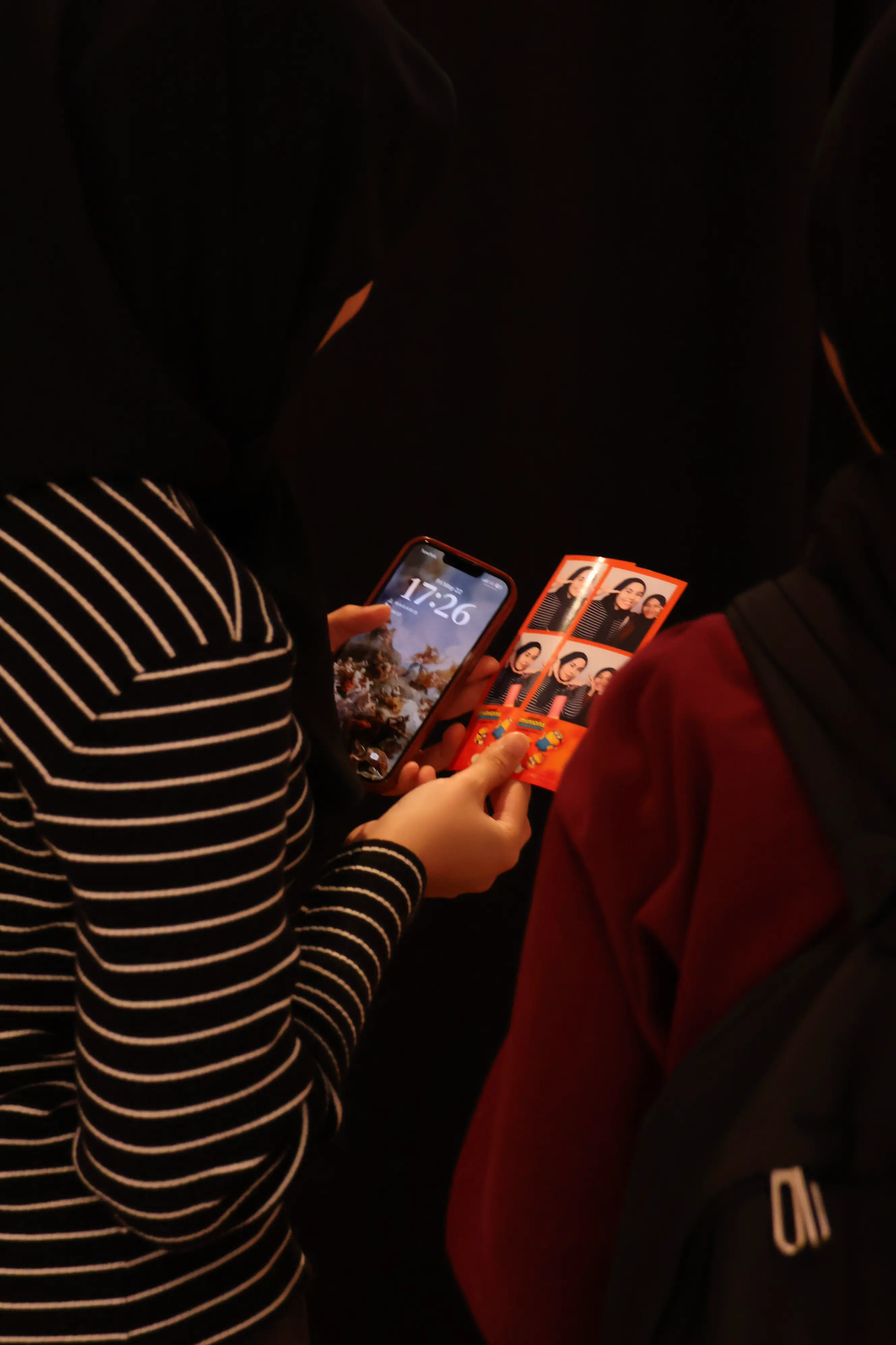 Guests comparing their Minions & Monsters photo strip with a phone in hand