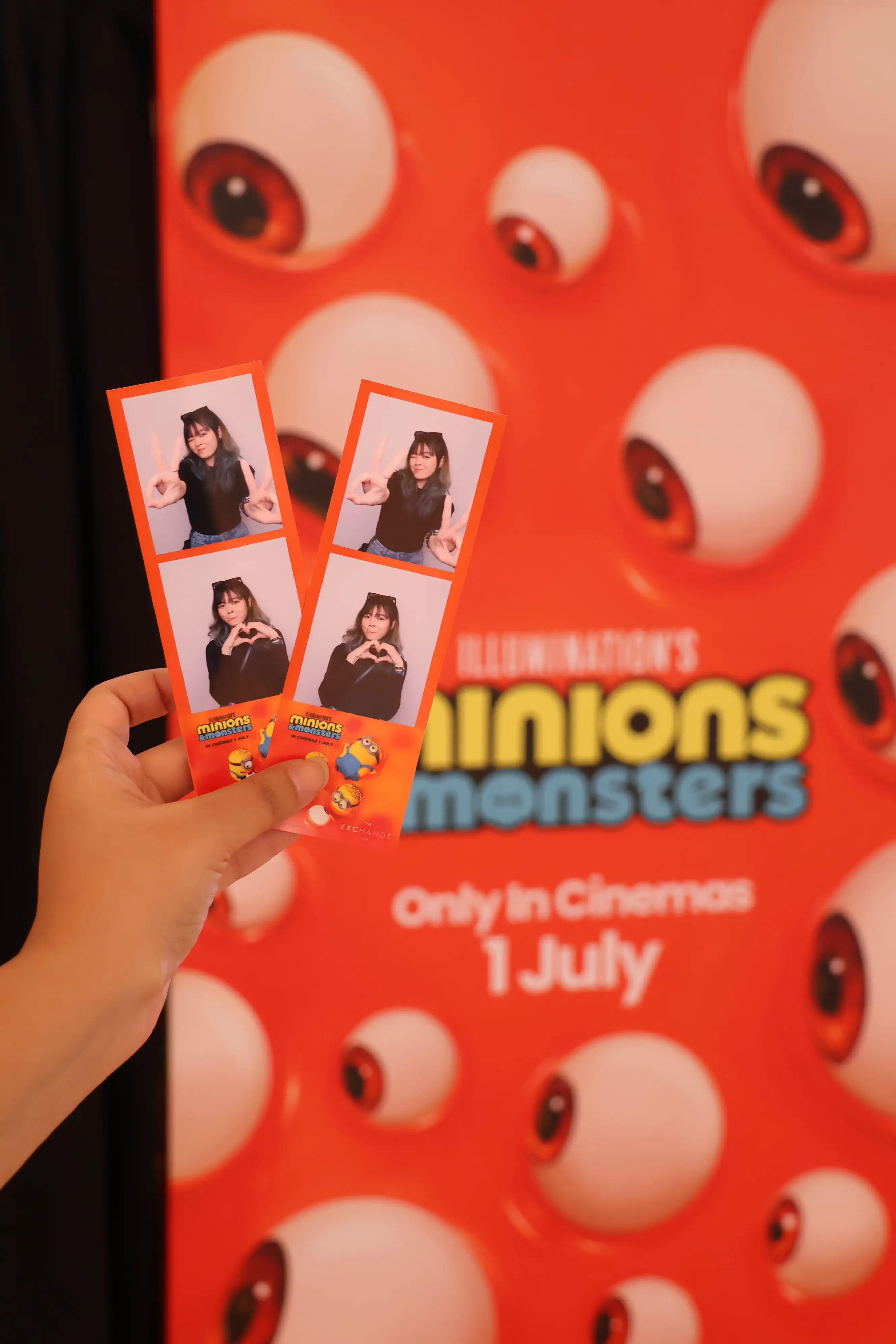 Two printed photo strips held in front of the Minions & Monsters backdrop