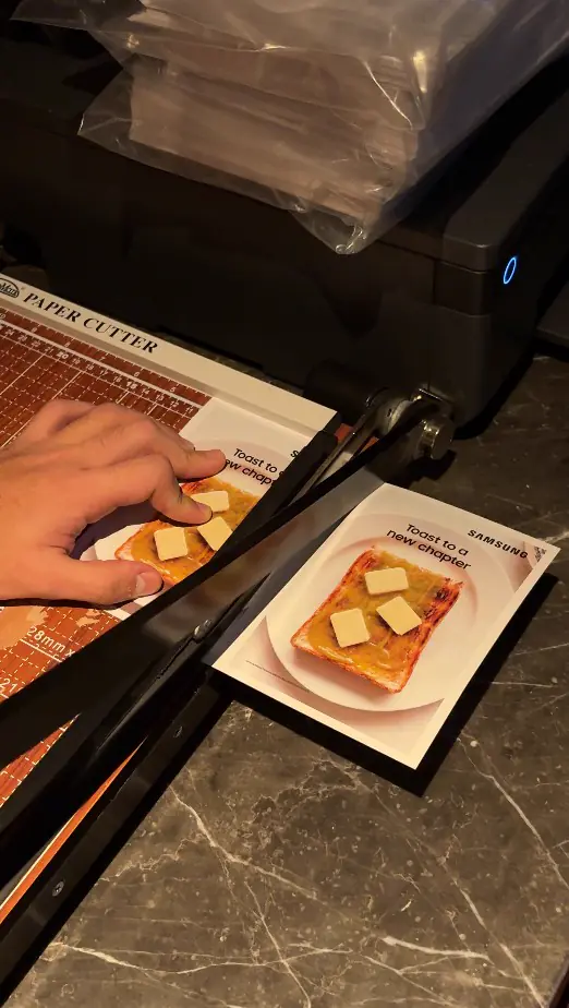 Printed Samsung postcards being trimmed on a paper cutter at the booth
