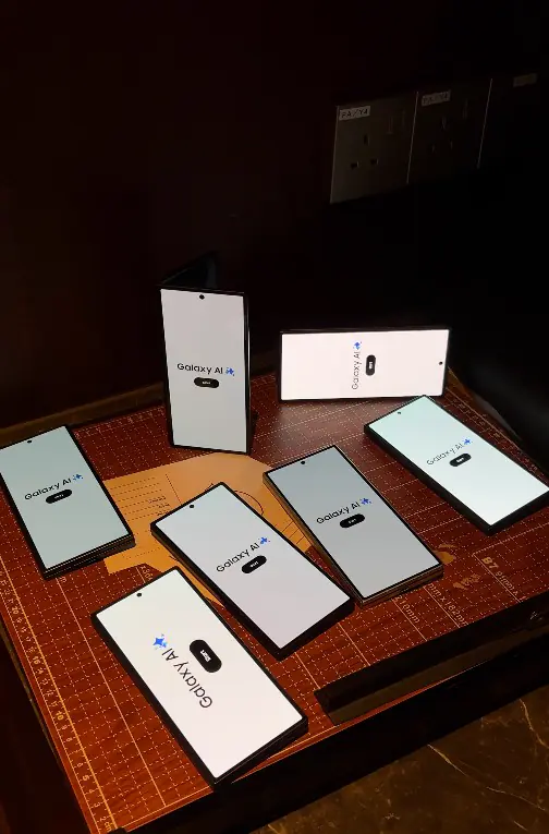 Galaxy AI phones arranged on a table showing the postcard booth start screen