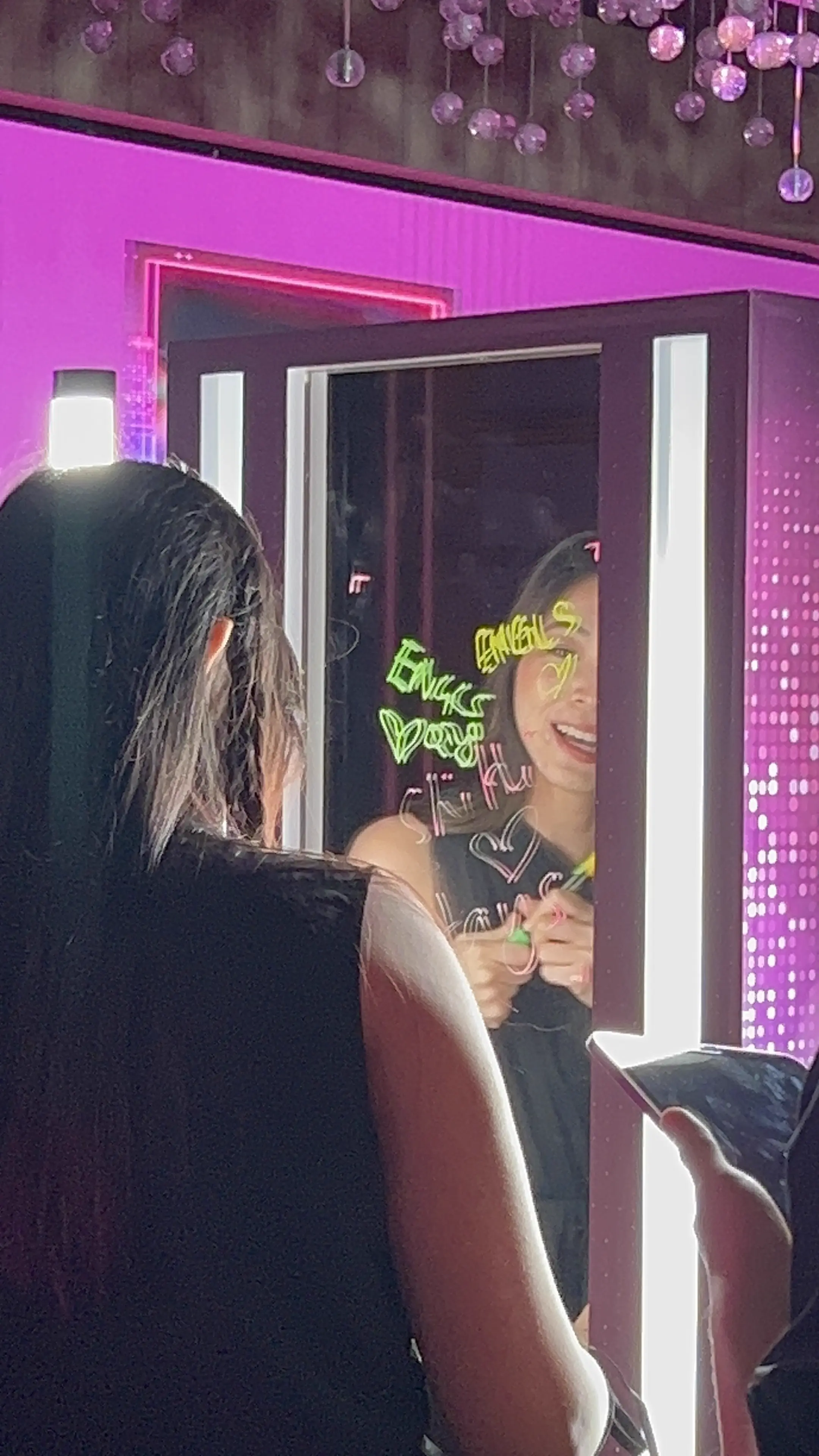 Guest drawing neon messages on the glass booth mirror under pink lights