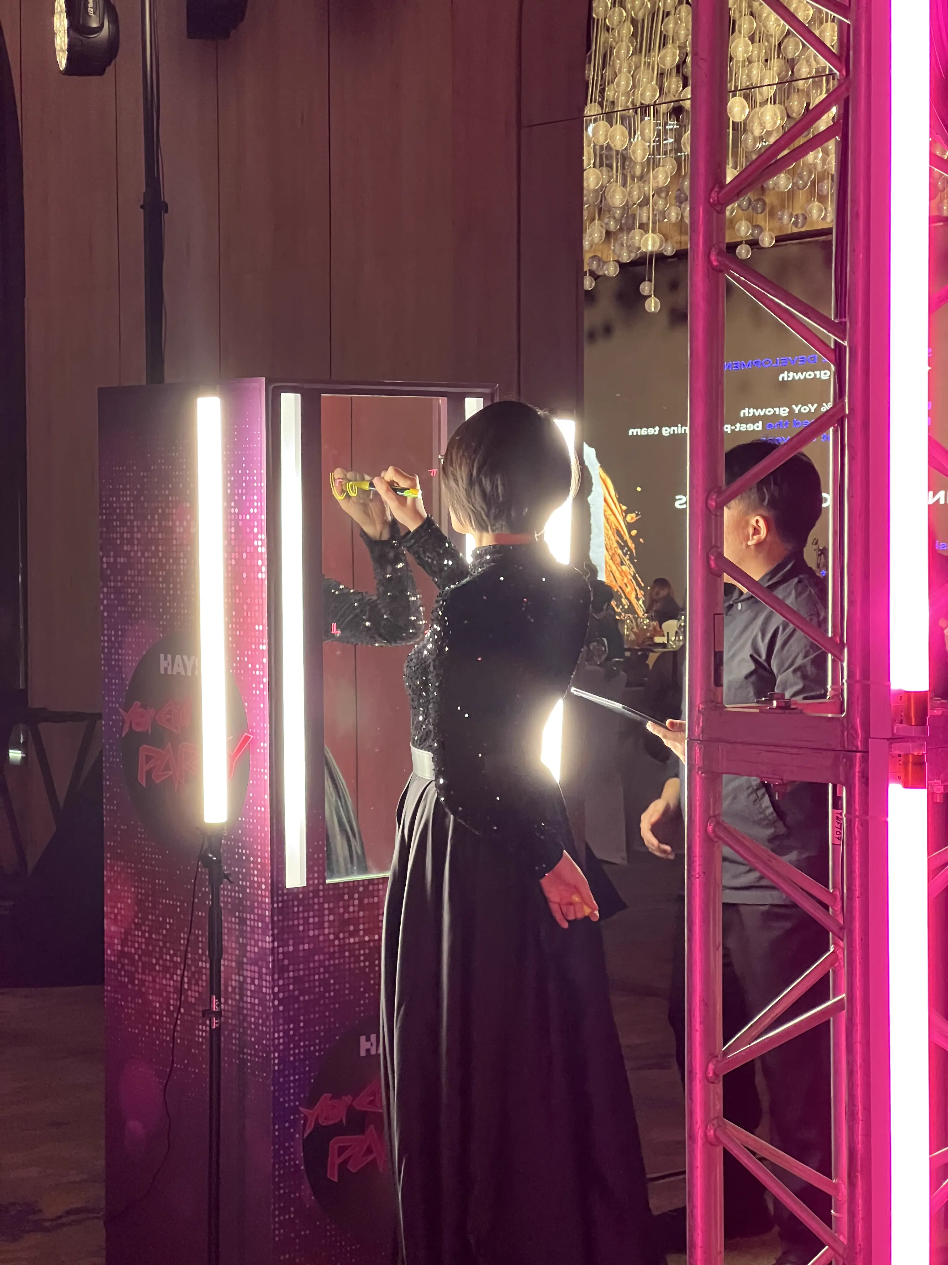 Guest writing on the HAYS Unveil Glass Booth with a fluorescent marker