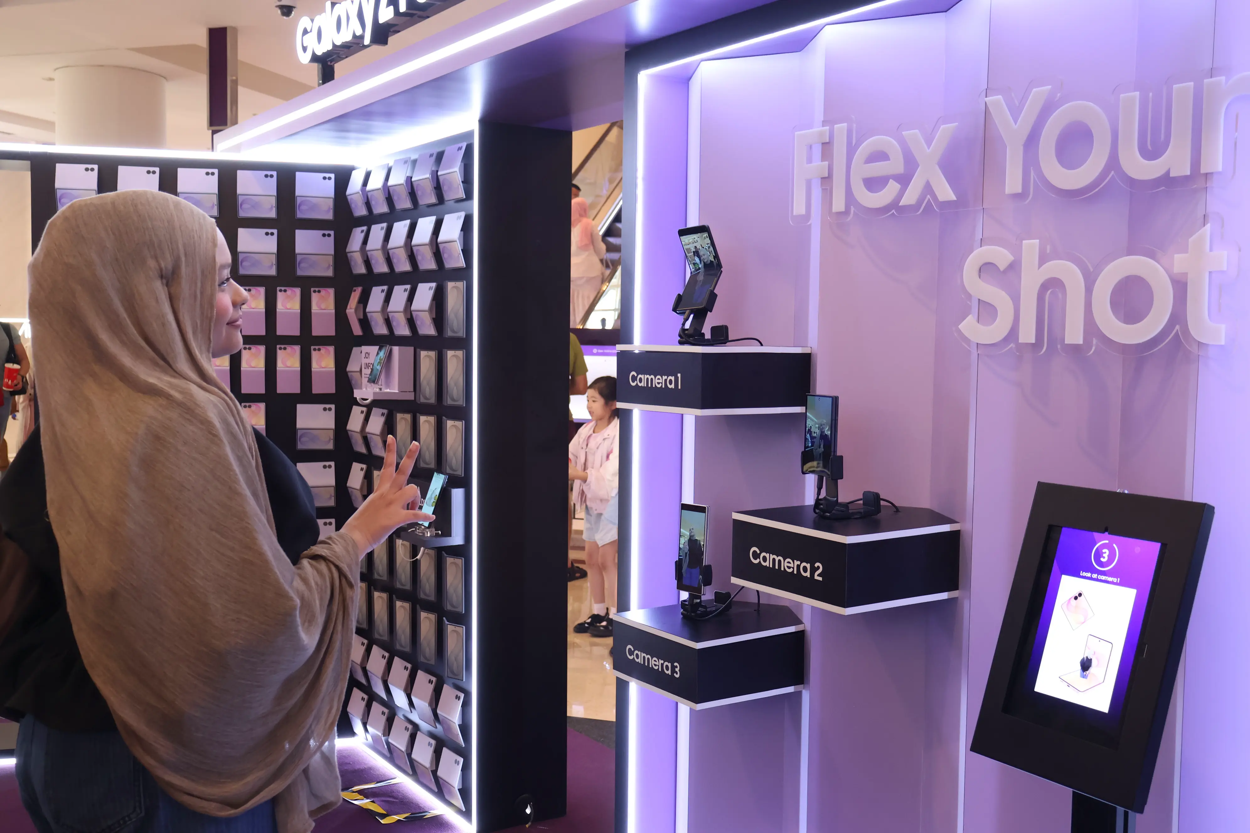 Guest posing at the Flex Your Shot wall beside the Galaxy Z phone display