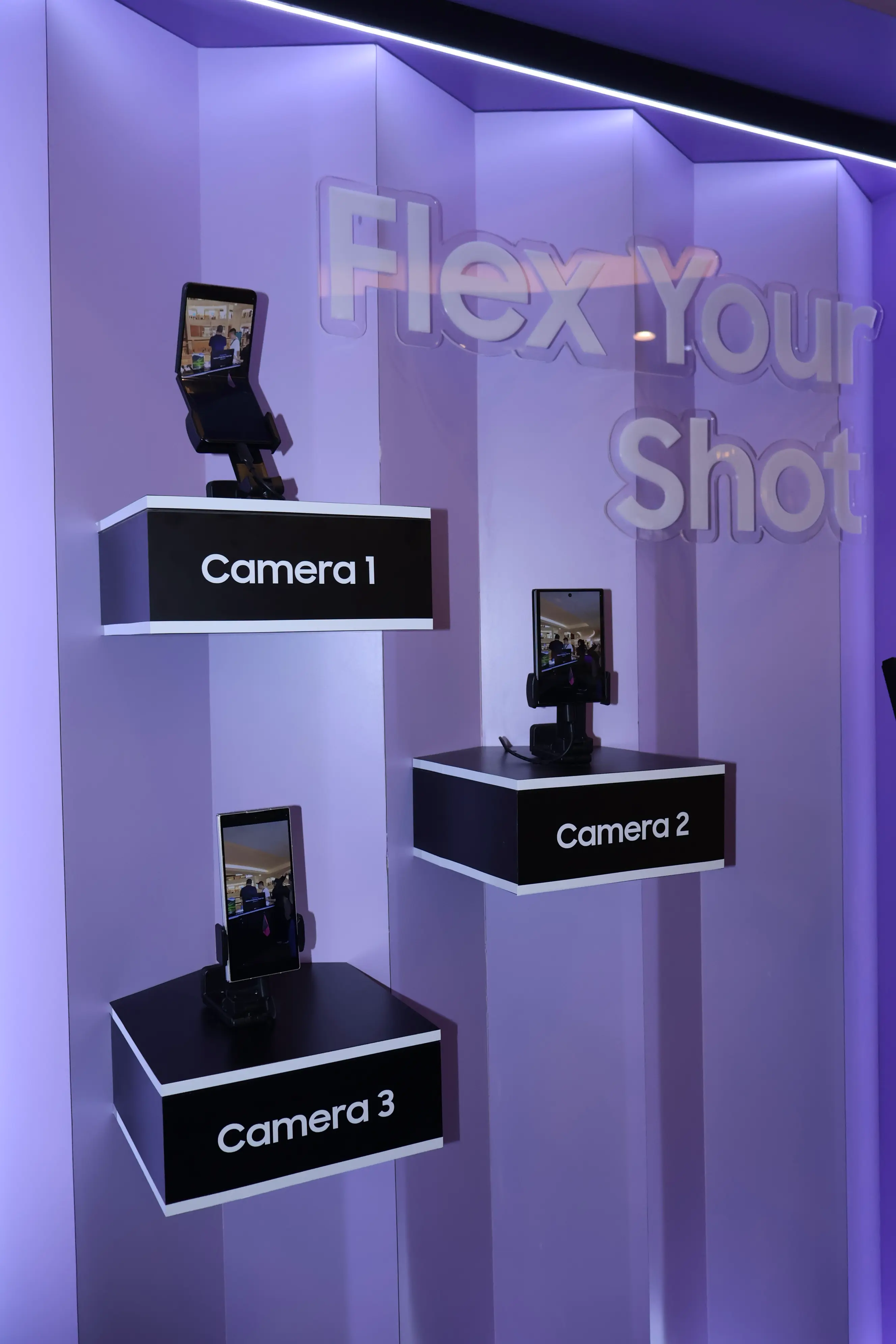 Three Galaxy Z foldable phones mounted as Camera 1, 2 and 3 on the booth wall